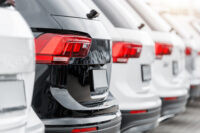 Back view many modern new SUV cars fleet stock at dealership parking lot. Automobile market production factory industry warehouse. Auto salvage buy and sell auction purchase seller platform