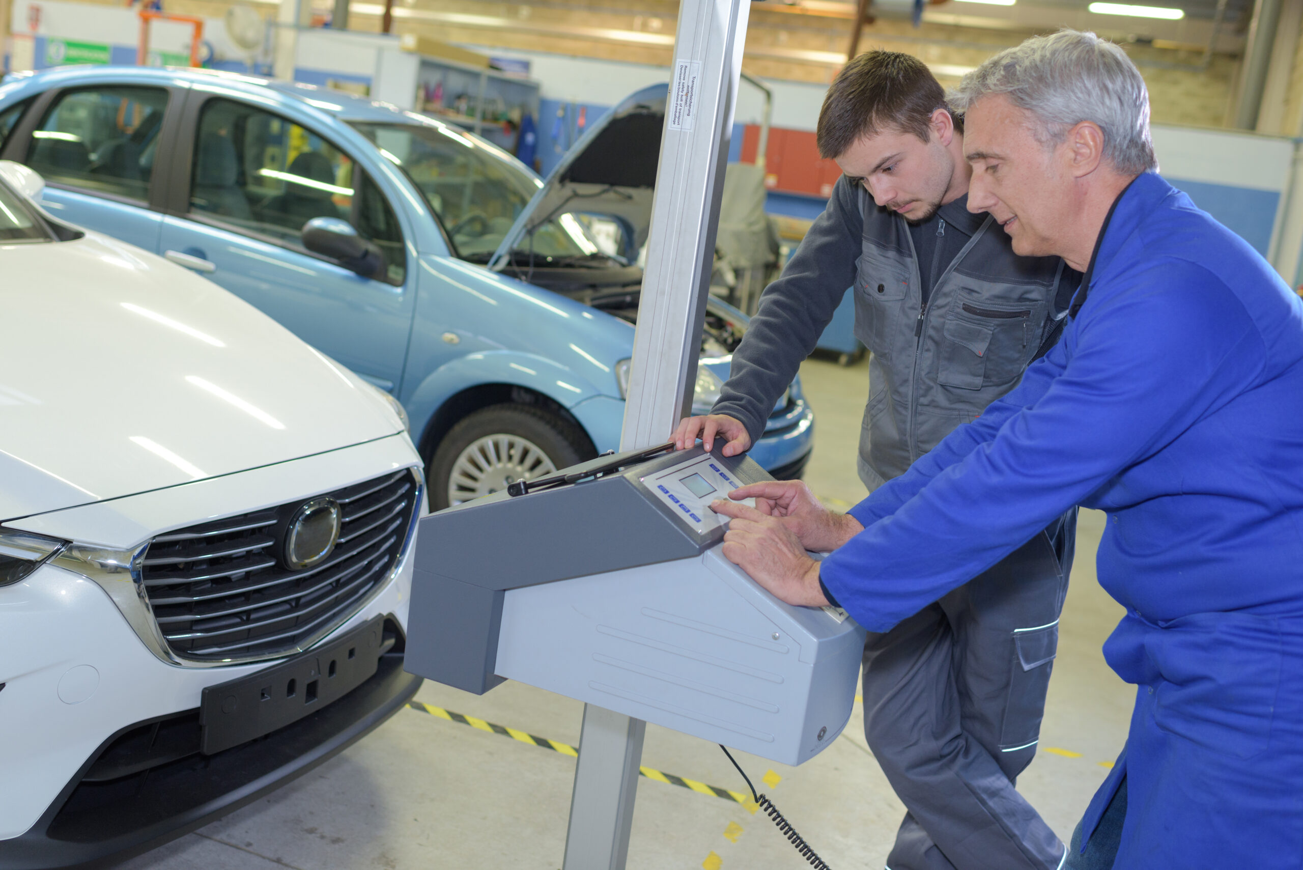 student with instructor repairing a car during apprenticeship